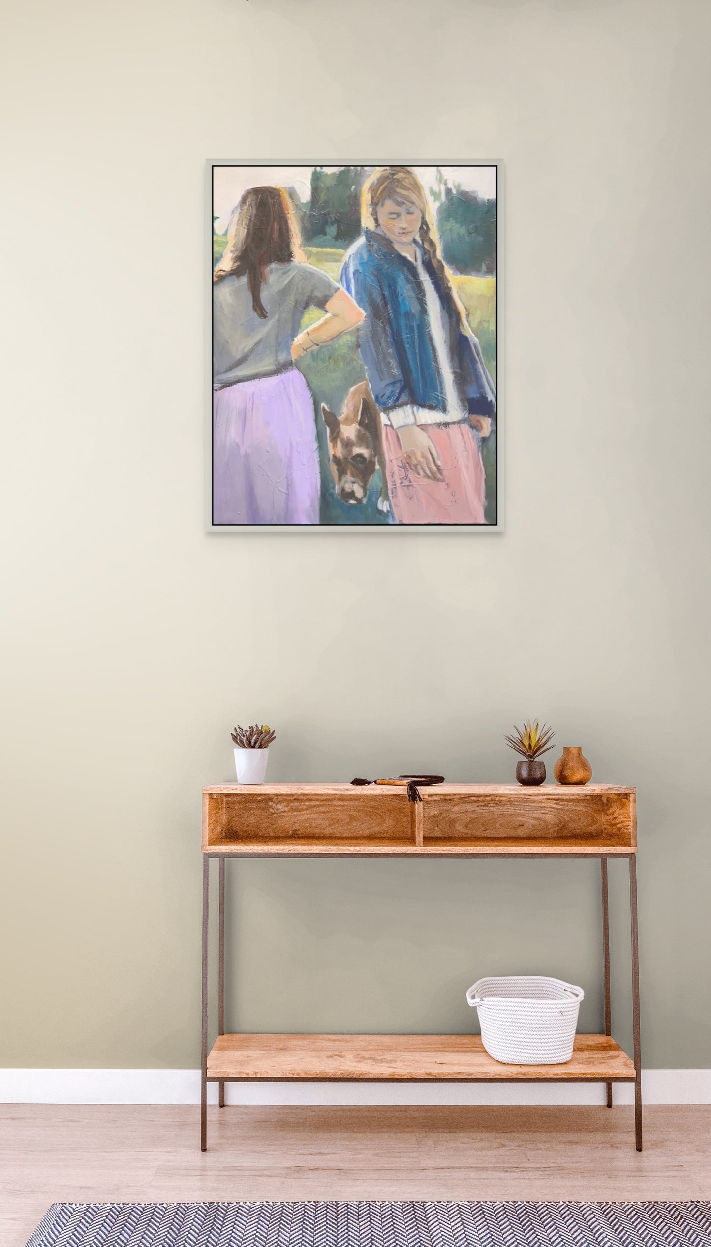 Framed artwork of two people and a dog on a wall above a wooden console table.