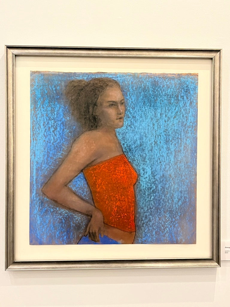 Framed artwork of a woman in an orange dress against a blue textured background