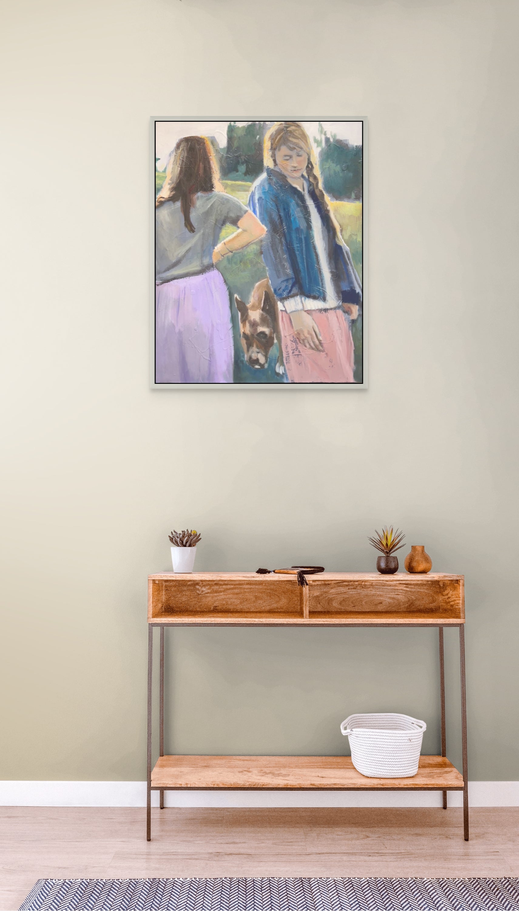 Framed artwork of two people and a dog on a wall above a wooden console table.
